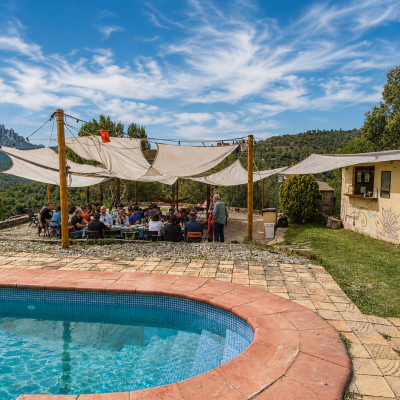 Piscina y glorieta con evento de empresa al fondo comiendo una paella